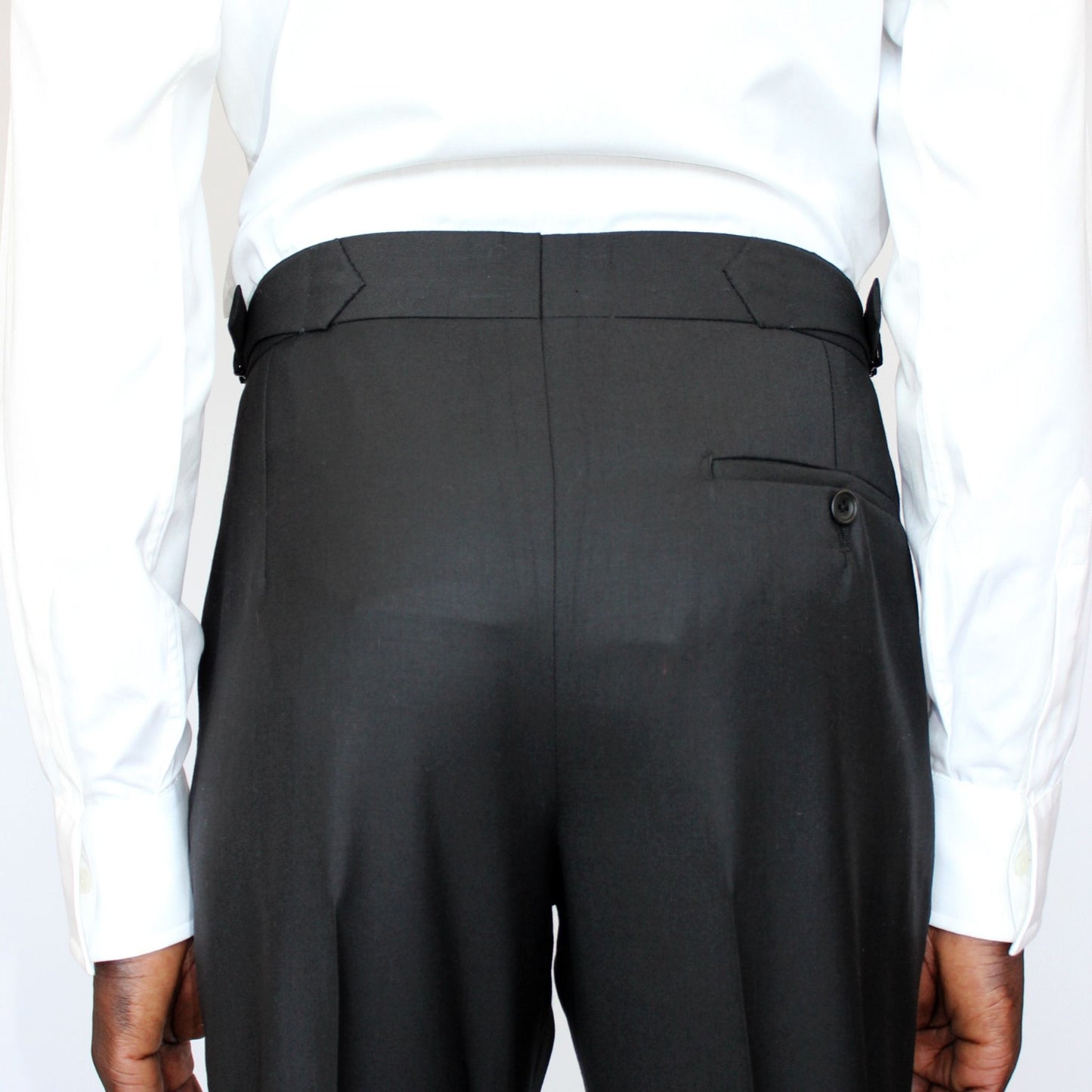 High-waisted tapered trousers by COLUCCI, expertly crafted by a Savile Row tailor from luxurious superfine merino wool with natural stretch. Featuring side adjusters for a perfect fit and a versatile jet-black hue, suitable for both office and casual wear.