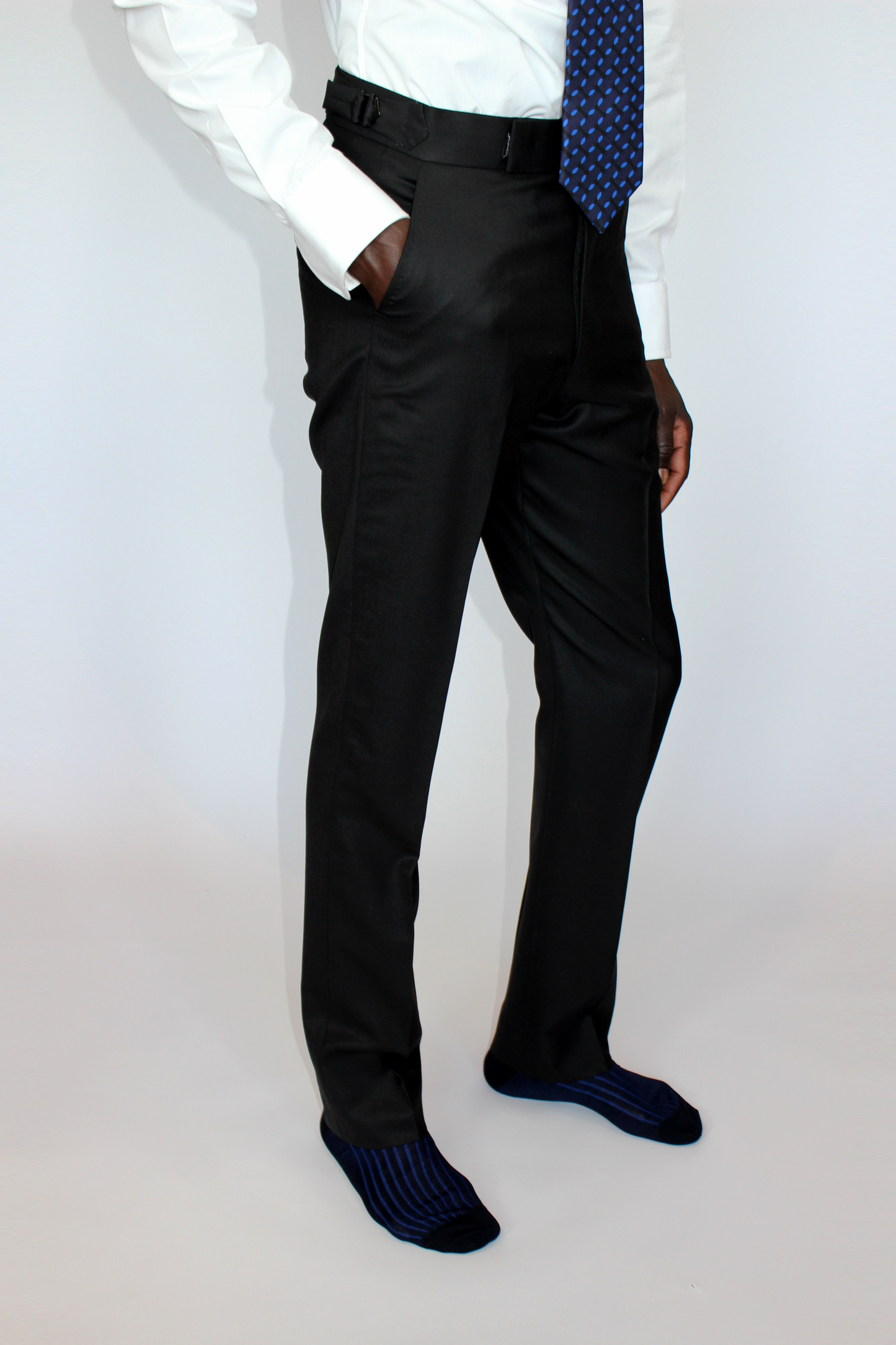 High-waisted tapered trousers by COLUCCI, expertly crafted by a Savile Row tailor from luxurious superfine merino wool with natural stretch. Featuring side adjusters for a perfect fit and a versatile jet-black hue, suitable for both office and casual wear.