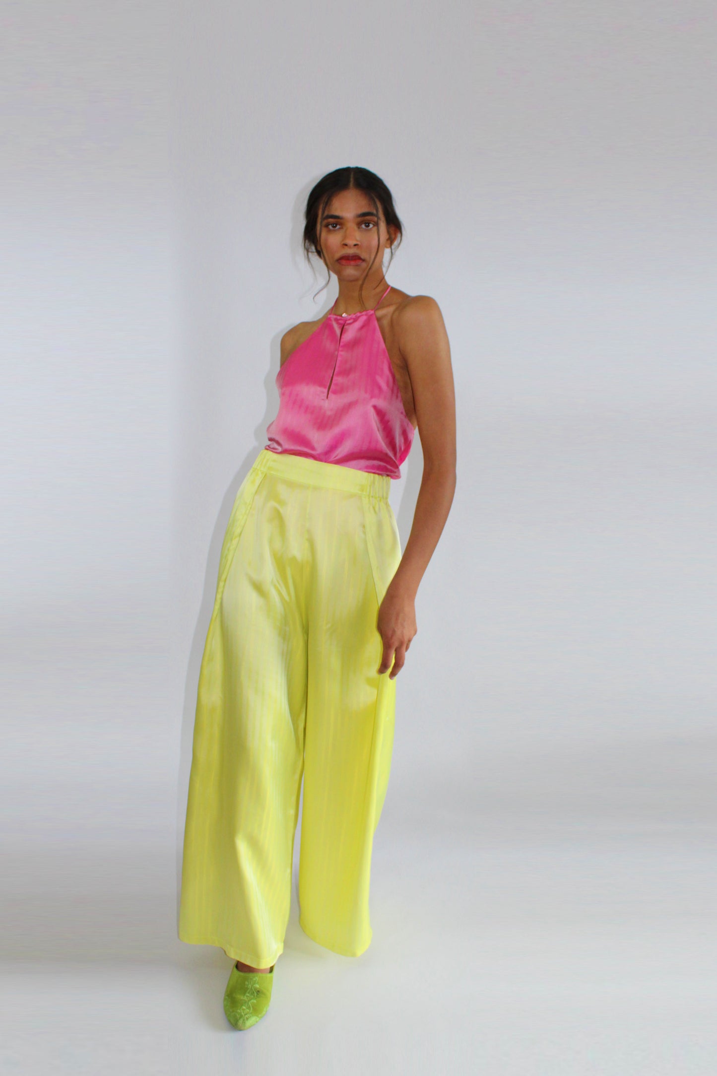 Palazzo trousers by COLUCCI, inspired by 1930s beach pyjamas, featuring a wide draping leg, high-waisted flat-front silhouette, and discreet side elastic waistband for comfort. Available in three eye-catching colors, crafted from designer deadstock fabrics for day-to-night elegance.