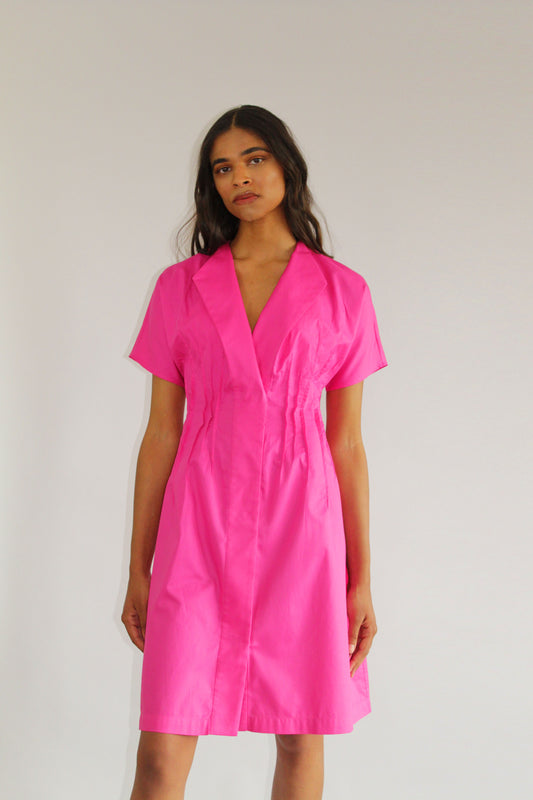 Pink cotton day dress by COLUCCI, crafted from sustainable designer-sourced deadstock fabric. Made-to-order in our London studio, featuring a tailored fit with snap-front closures and a pin-tuck waist for elegance. Ideal for sunny brunches or weekday errands, combining style and comfort.