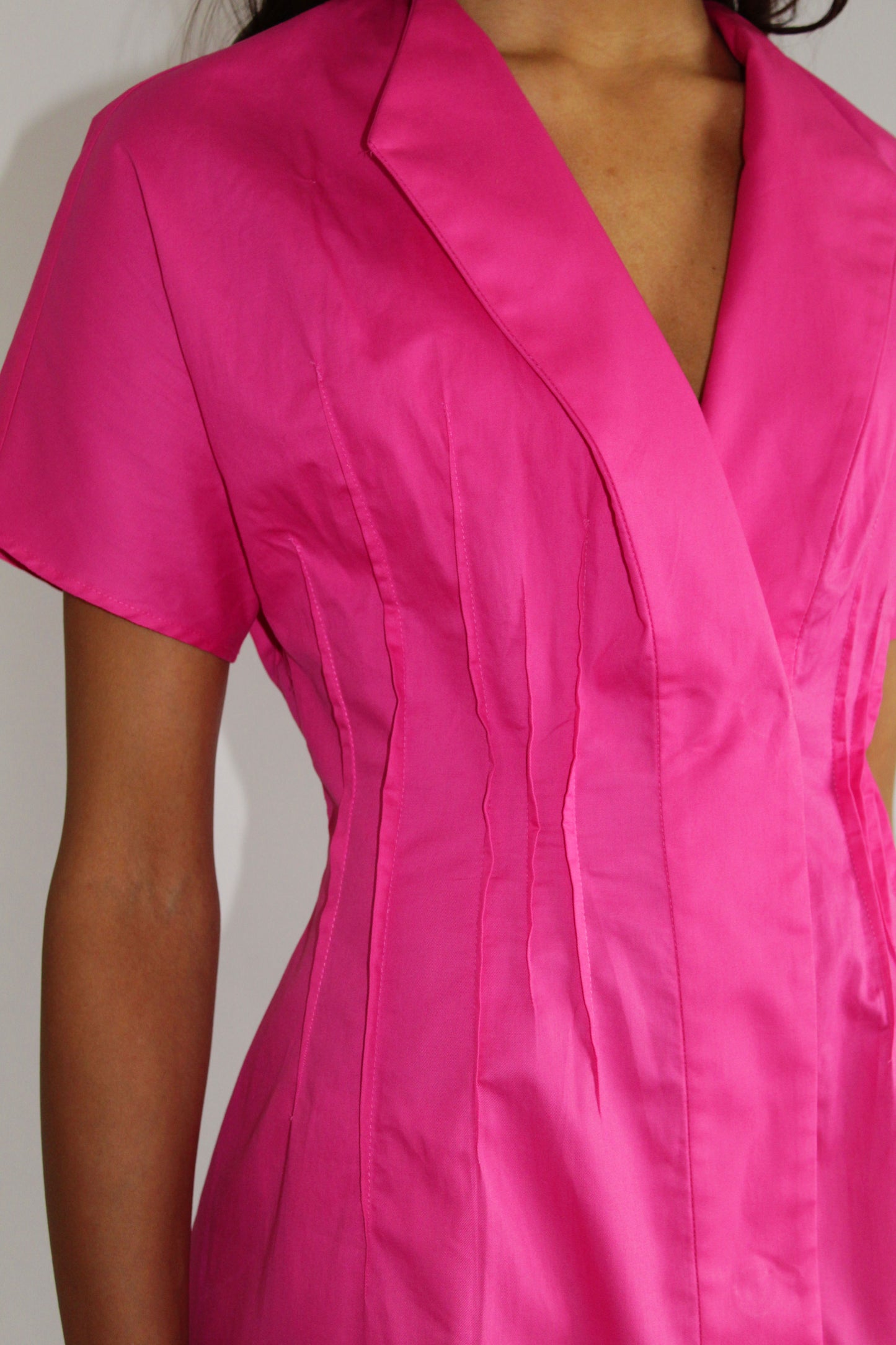 Pink cotton day dress by COLUCCI, crafted from sustainable designer-sourced deadstock fabric. Made-to-order in our London studio, featuring a tailored fit with snap-front closures and a pin-tuck waist for elegance. Ideal for sunny brunches or weekday errands, combining style and comfort.