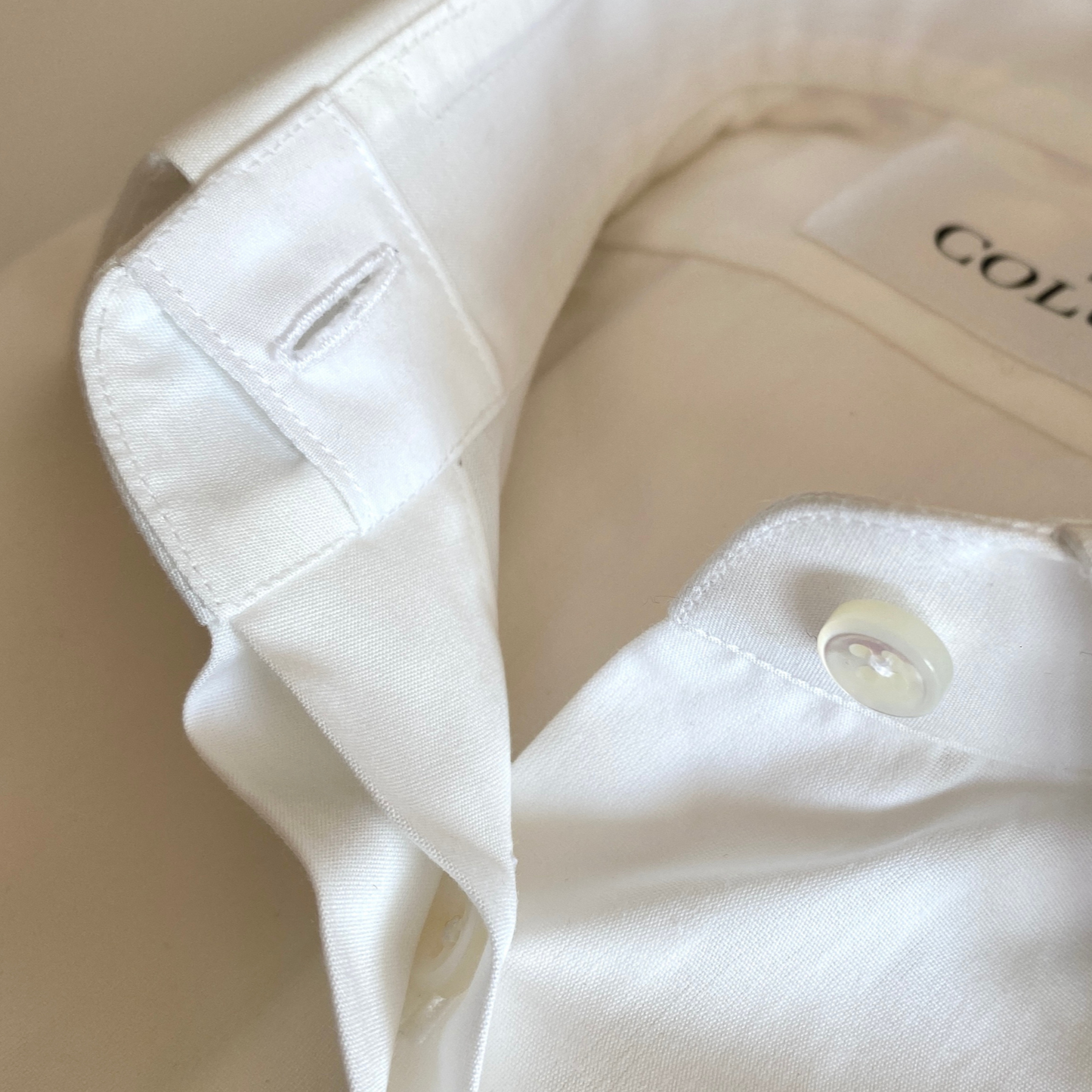 White dress shirt for women by COLUCCI, featuring a wide cutaway collar and concealed placket for refined sophistication. Unique concealed buttons on the collar and cuffs add modern flair, with each button crafted from mother of pearl for a luxurious touch. Made-to-order by our Savile Row tailor, ensuring a perfect fit tailored to the customer’s measurements.