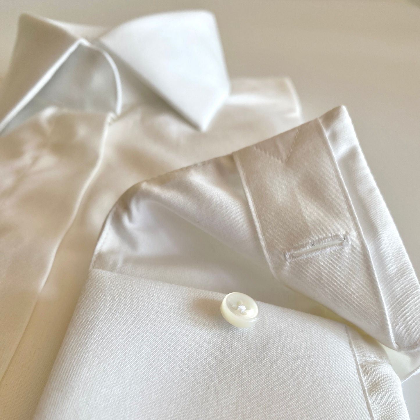 White dress shirt for women by COLUCCI, featuring a wide cutaway collar and concealed placket for refined sophistication. Unique concealed buttons on the collar and cuffs add modern flair, with each button crafted from mother of pearl for a luxurious touch. Made-to-order by our Savile Row tailor, ensuring a perfect fit tailored to the customer’s measurements.