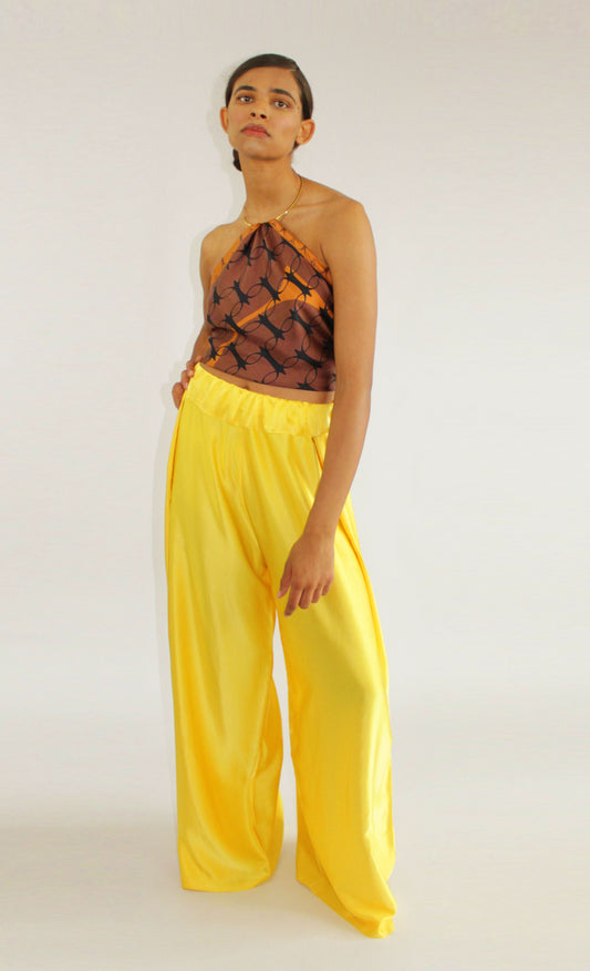 Yellow silk palazzo trousers by COLUCCI, crafted from premium crepe silk satin for luxury. Featuring a high-waisted, flat-front silhouette and discreet side elastic waistband for comfort and a flattering fit. Versatile for day-to-night styling, pair with a casual tee and sandals or a blouse and heels for a refined look. A luxurious wardrobe staple blending elegance and versatility.