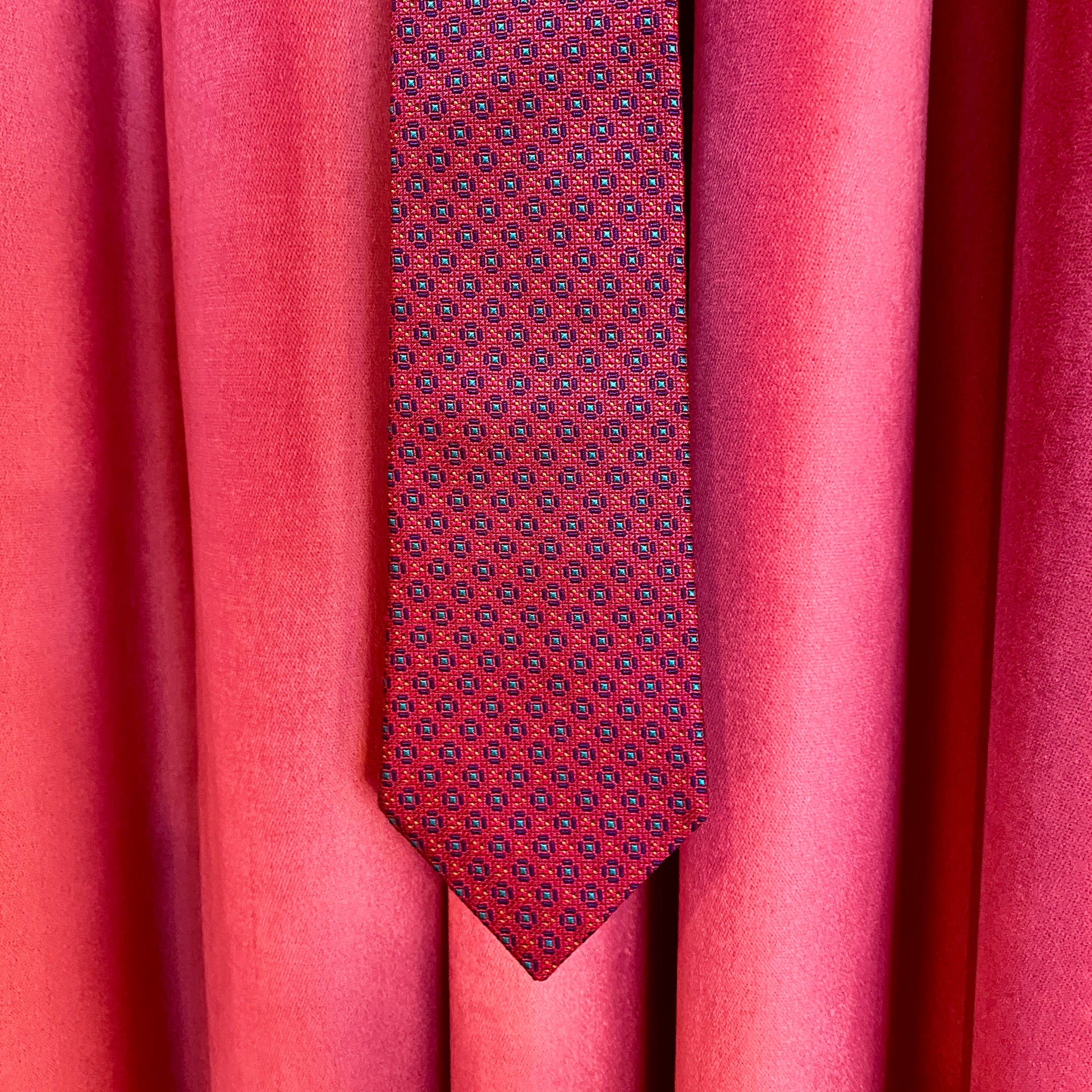 Red patterned tie against a red curtain background